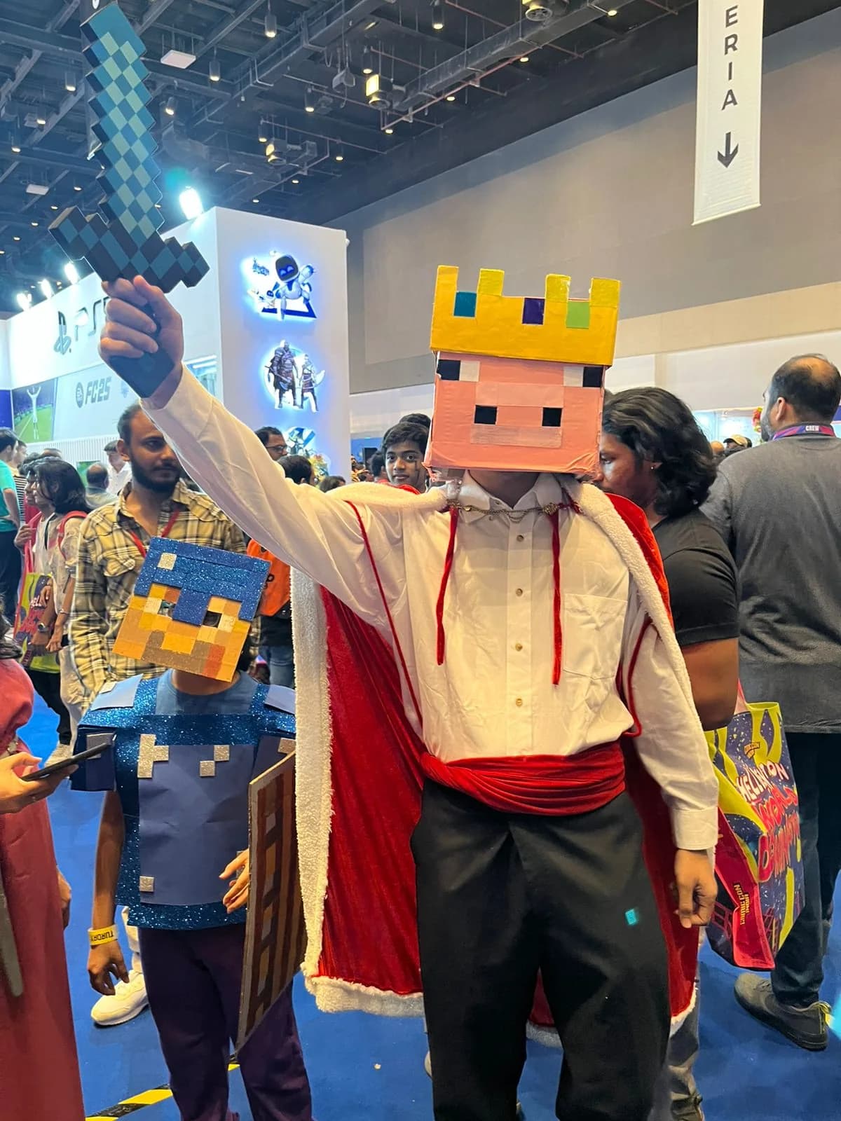 Pig-king cosplay raising a large pixel-style sword at a convention