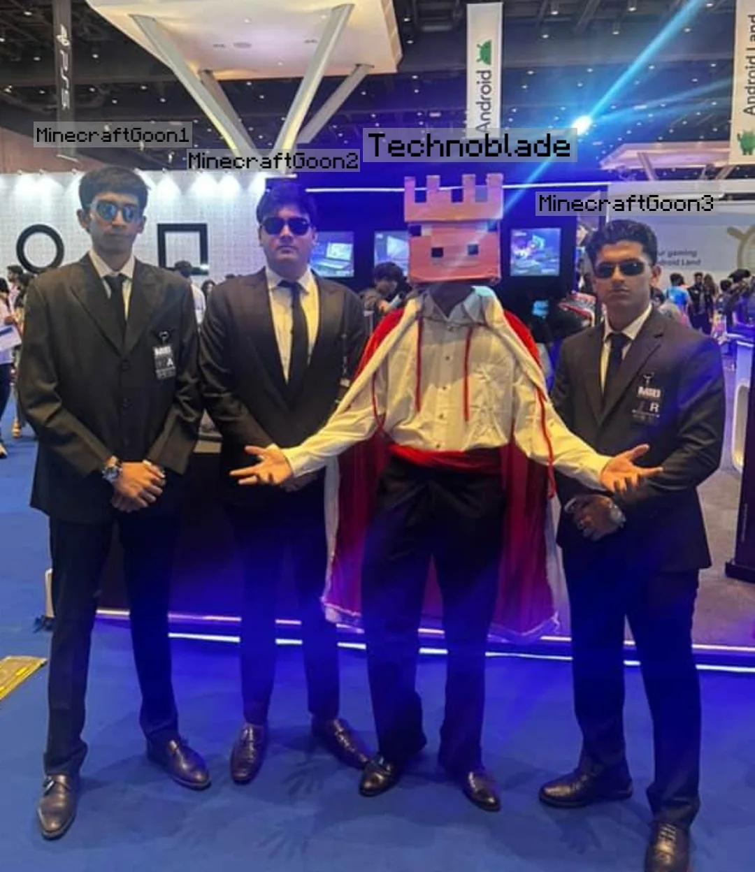 Group convention photo with the pig-king cosplay centered between three people in dark suits