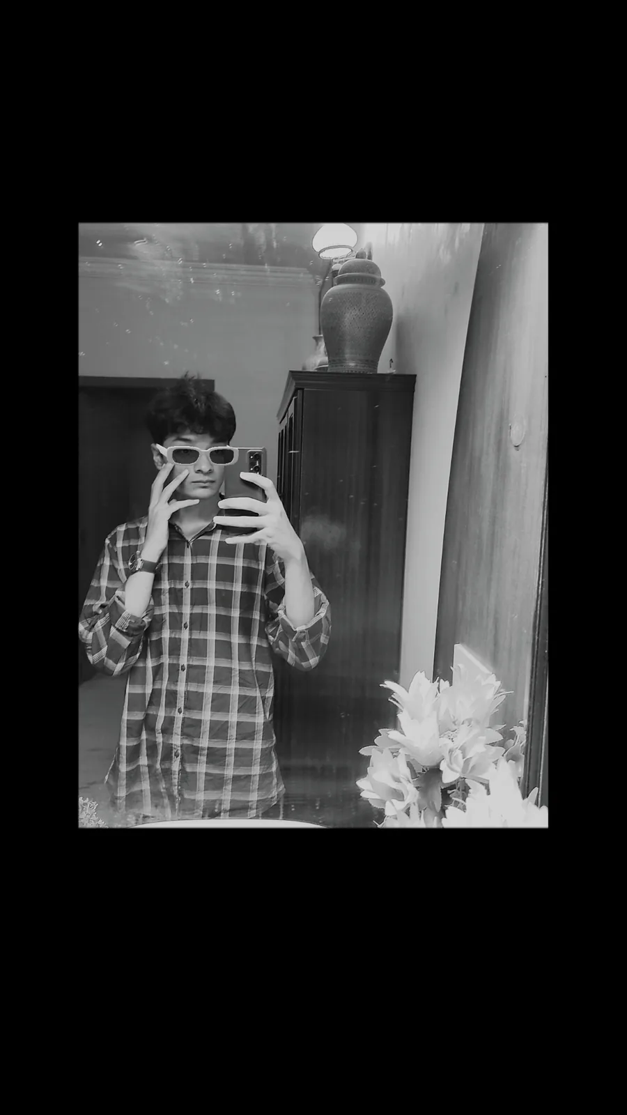 Black-and-white mirror portrait in a checkered shirt and sunglasses